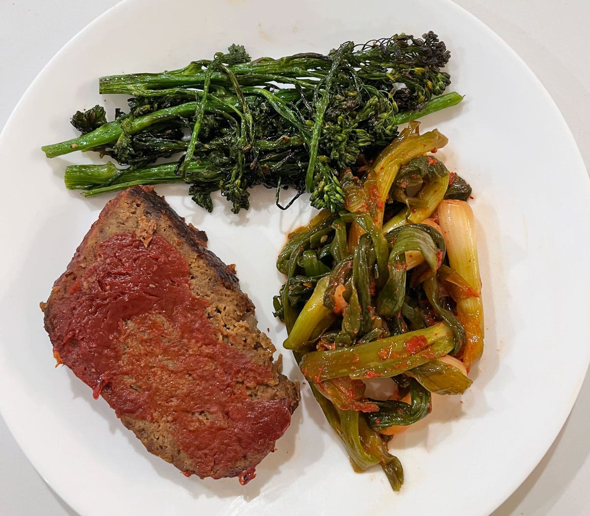 Leftover keto meatloaf is served with broccolini and kimchi.