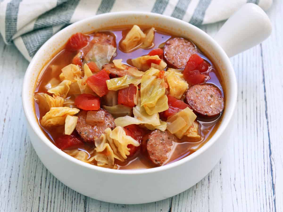 Cabbage soup is served in a white soup bowl.