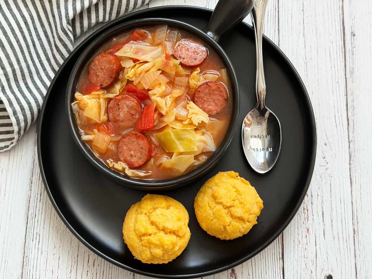 Cabbage soup is served with cornbread muffins.