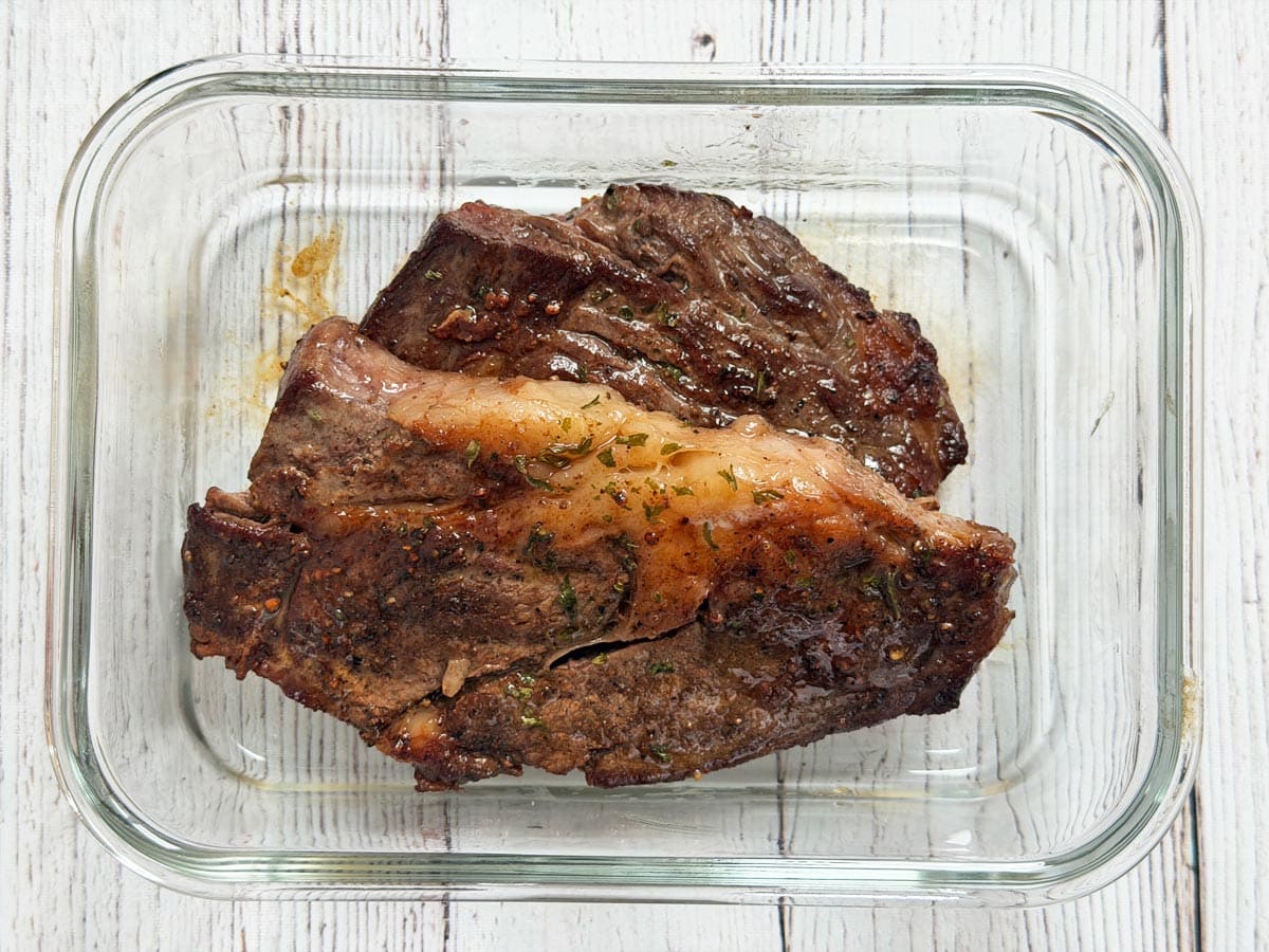 Chuck eye steak leftovers are stored in a glass container.