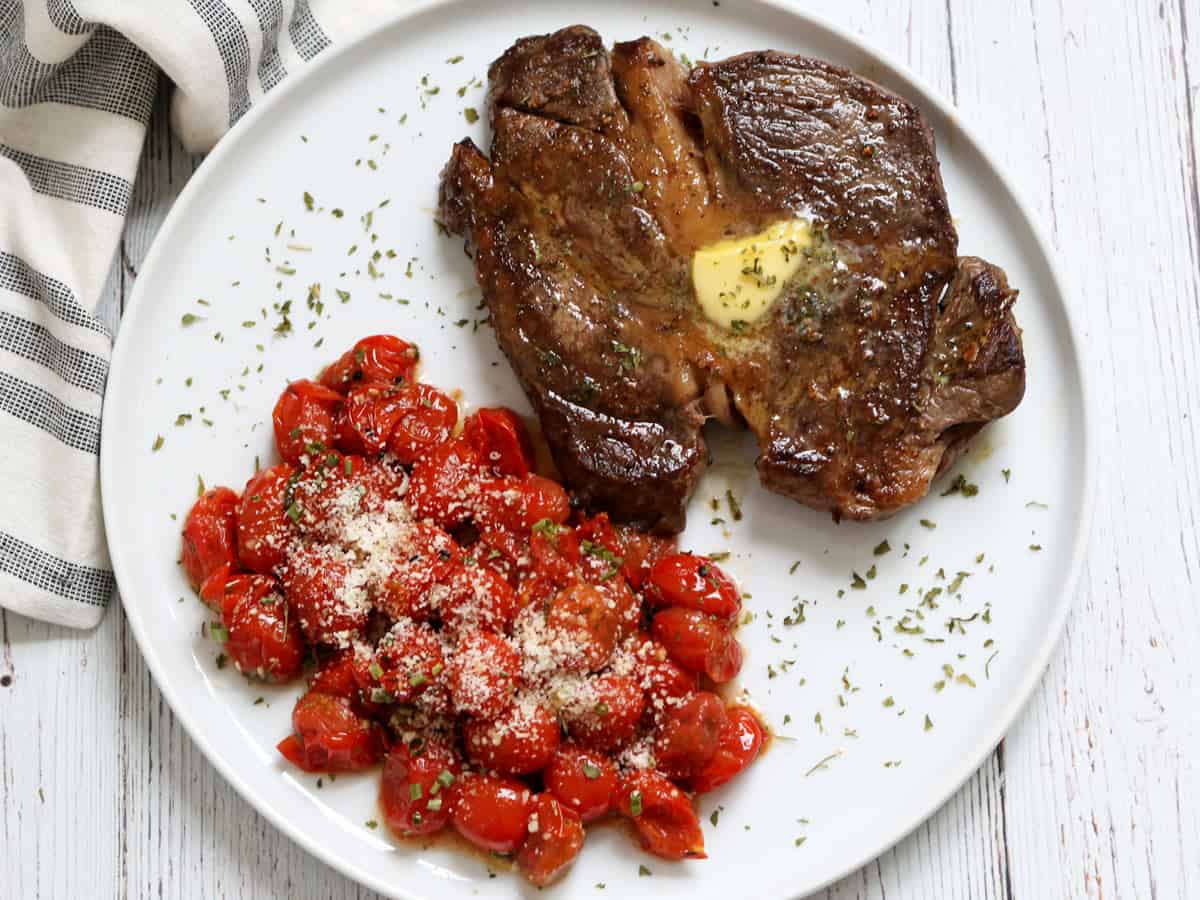 Chuck eye steak is served with roasted cherry tomatoes.