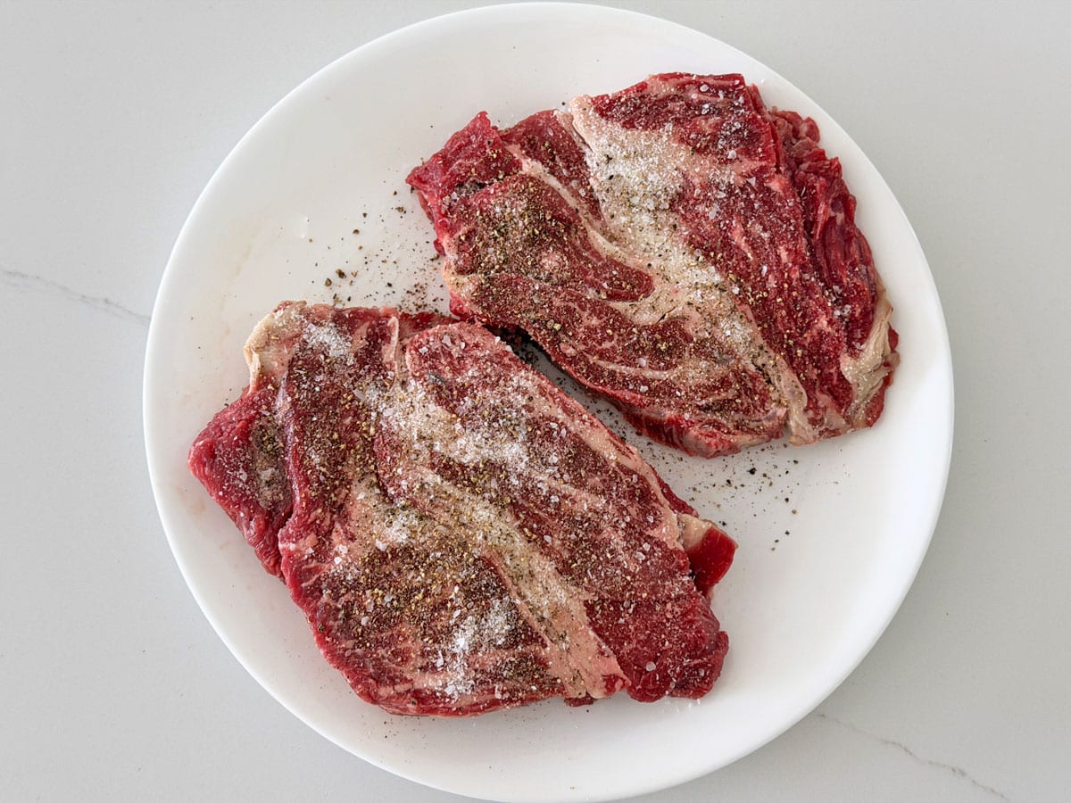 Two chuck eye steaks were seasoned with kosher salt and black pepper.