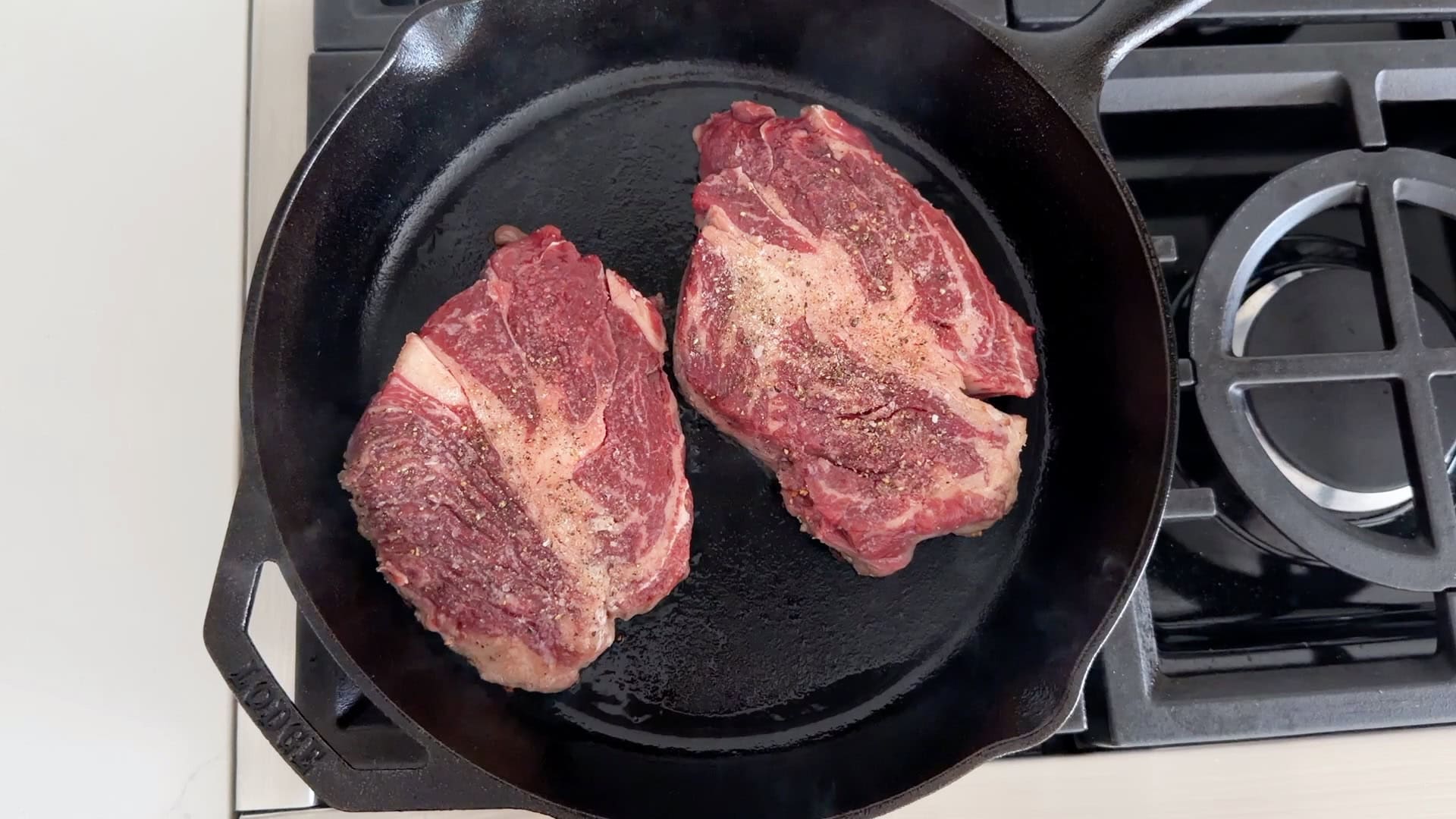 Two chuck eye steaks in a cast-iron skillet.