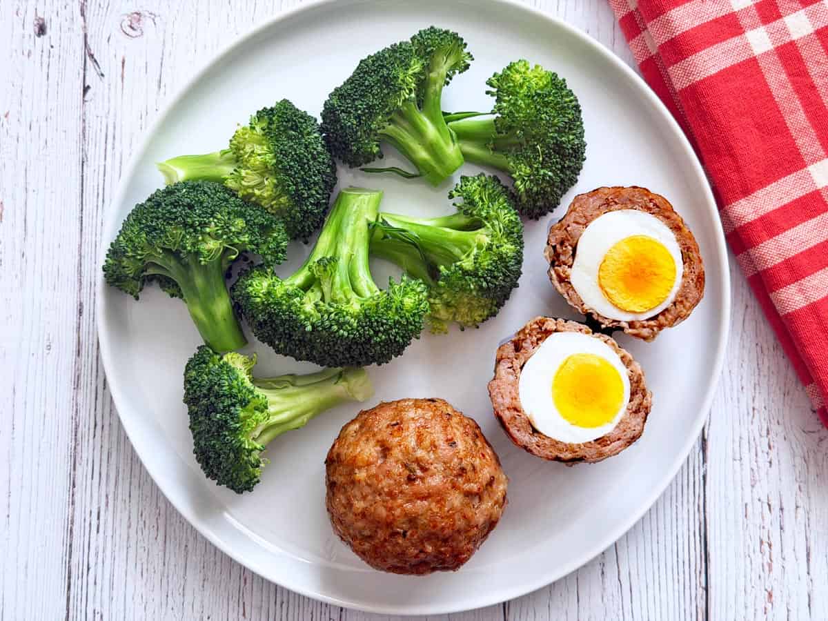 Scotch eggs are served with broccoli.