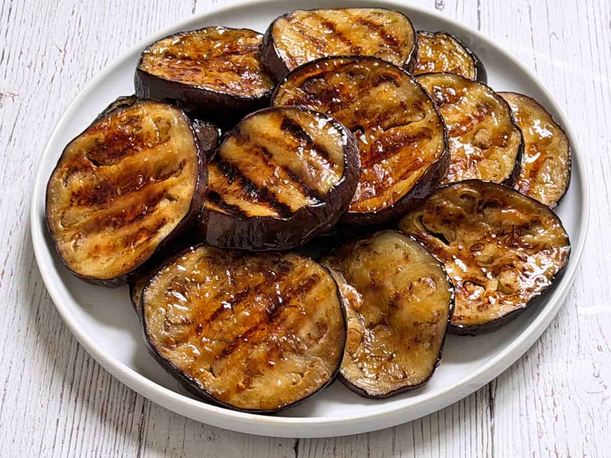 Grilled eggplant is served on a white plate.
