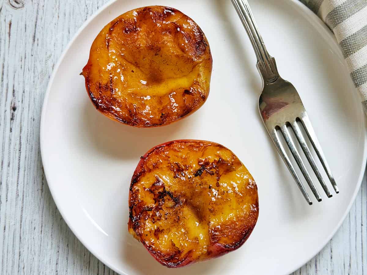 Two peaches that were cooked in a cast-iron skillet.