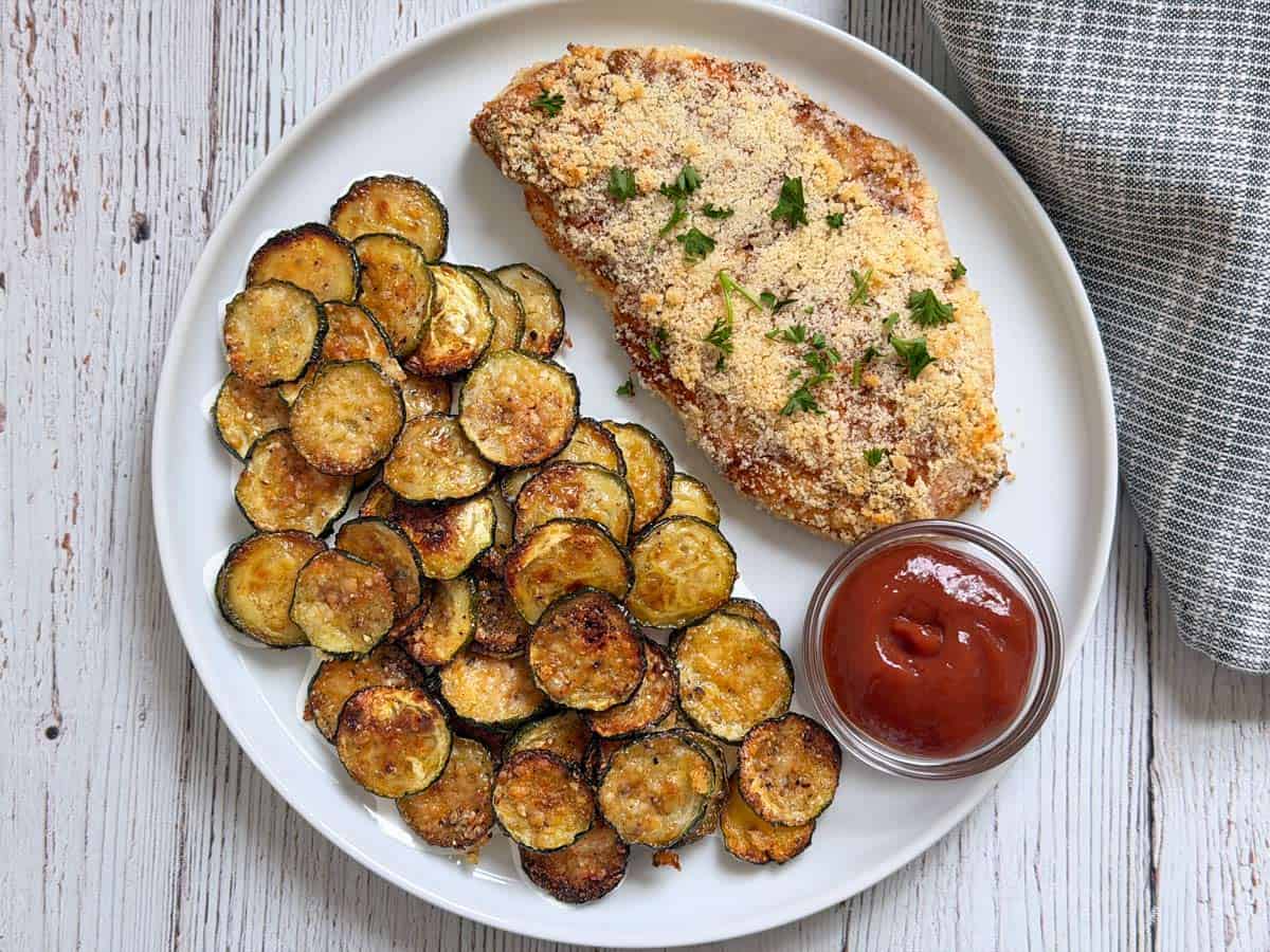 Parmesan crusted chicken is served with zucchini chips.