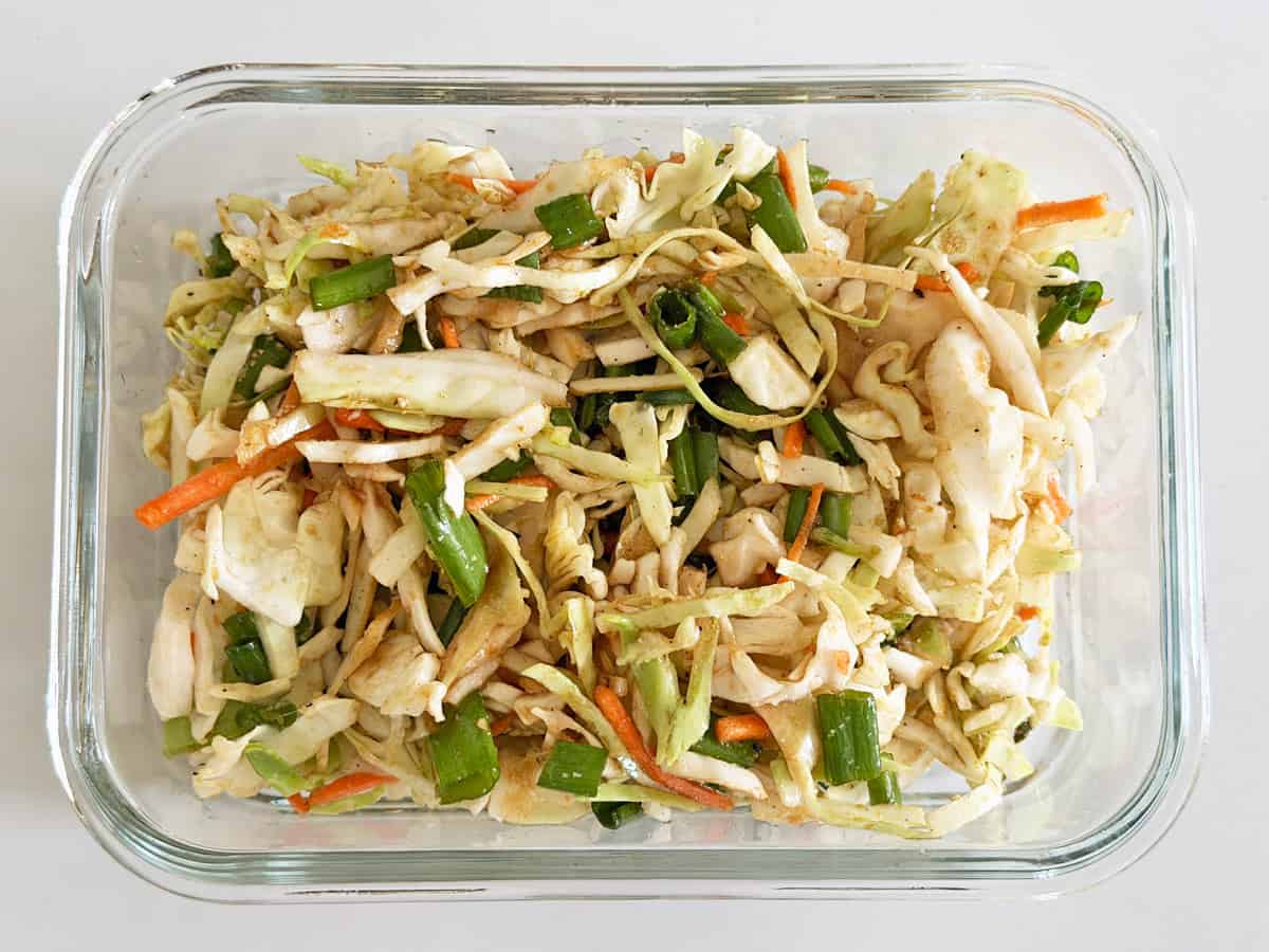 Asian cabbage salad is stored in a glass container.