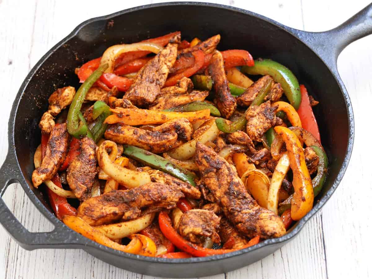Chicken fajitas in a cast-iron skillet.