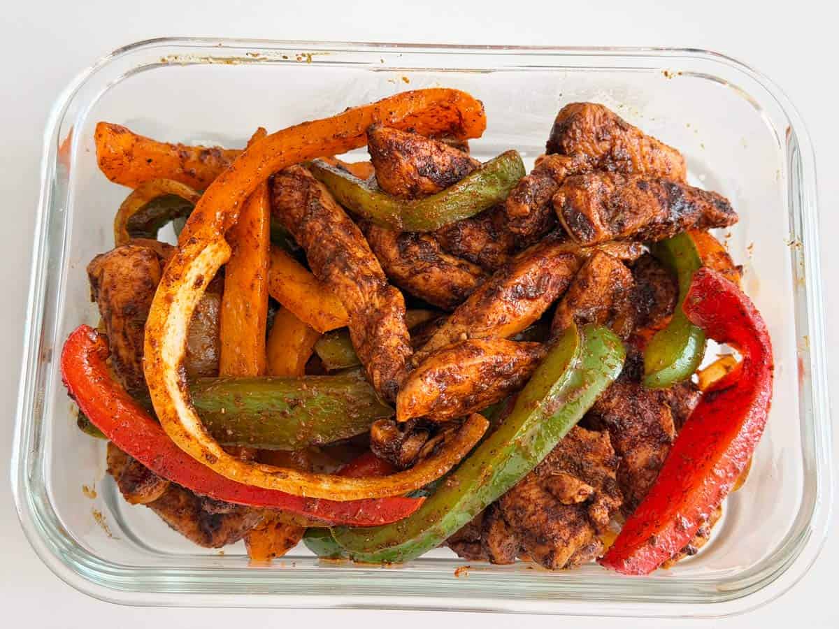 Chicken fajitas leftovers in a glass container.
