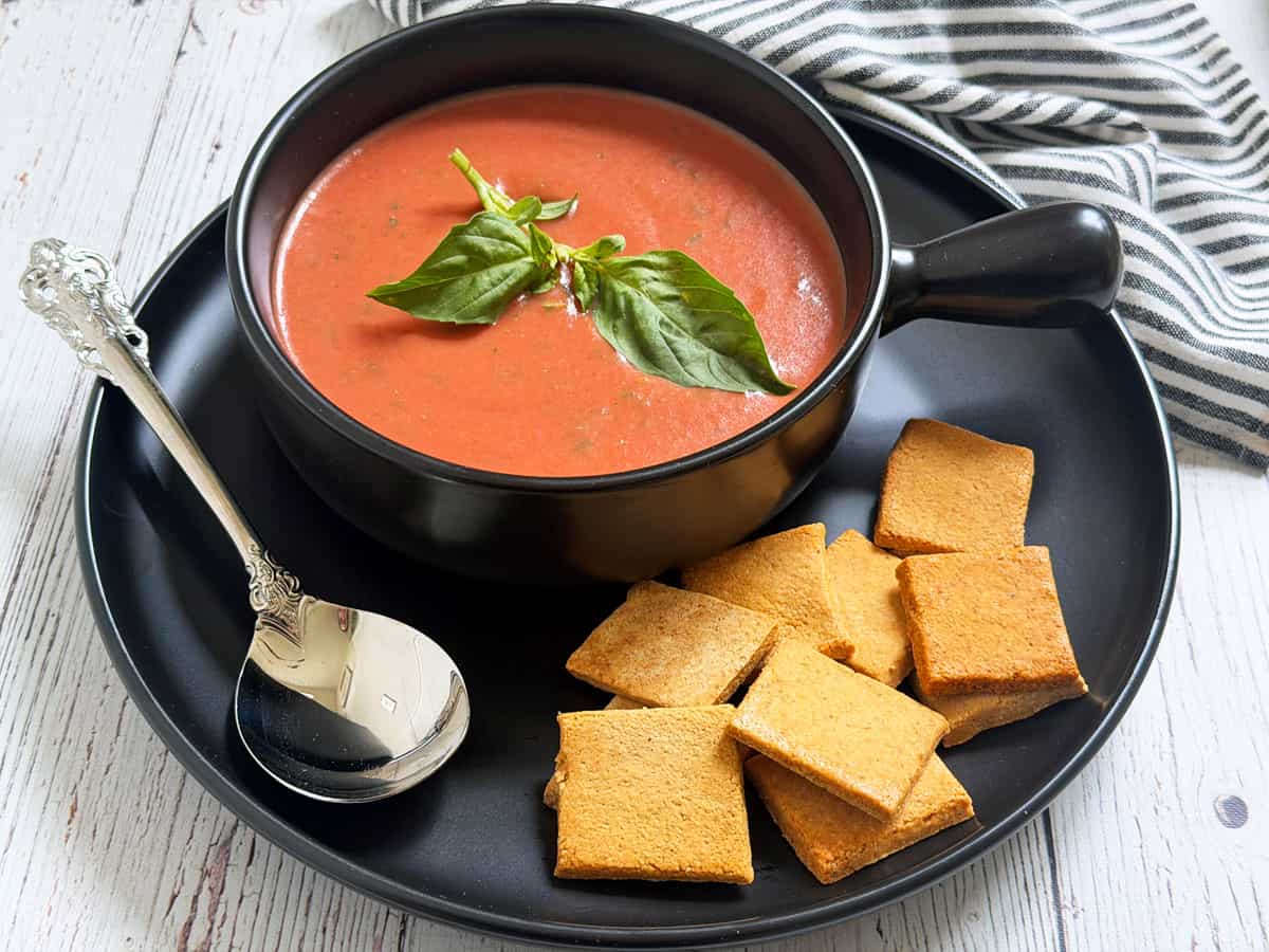 Cold tomato soup is served with crackers.