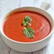 Cold tomato soup is served in a white bowl.