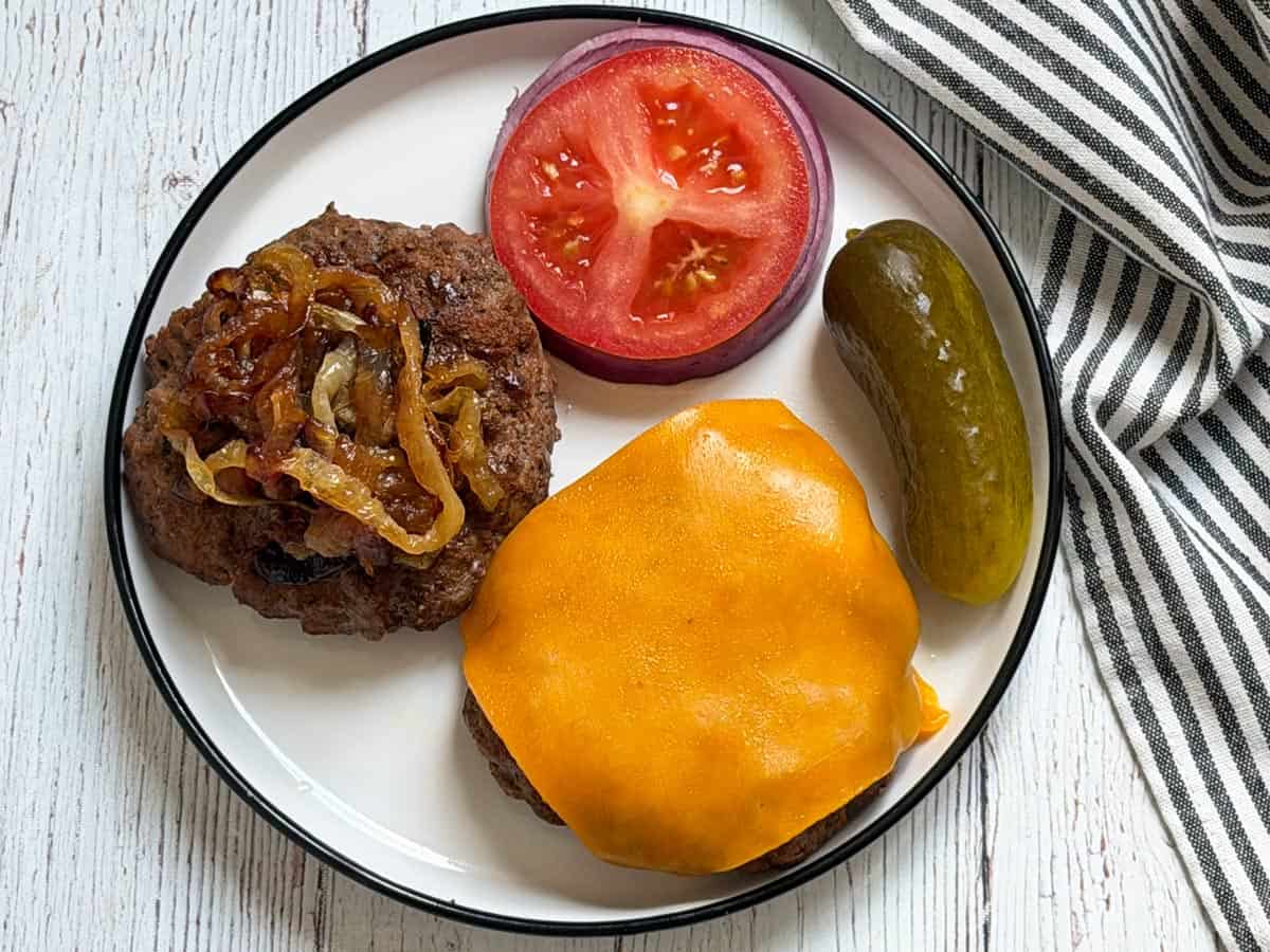 Grilled burgers are topped with cheese and caramelized onions.
