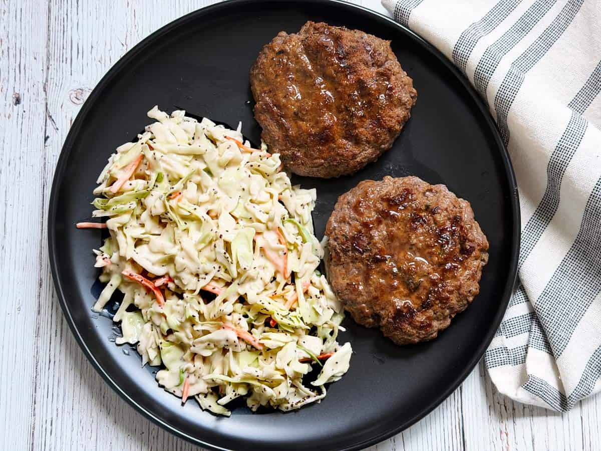 Grilled burgers are served with coleslaw.