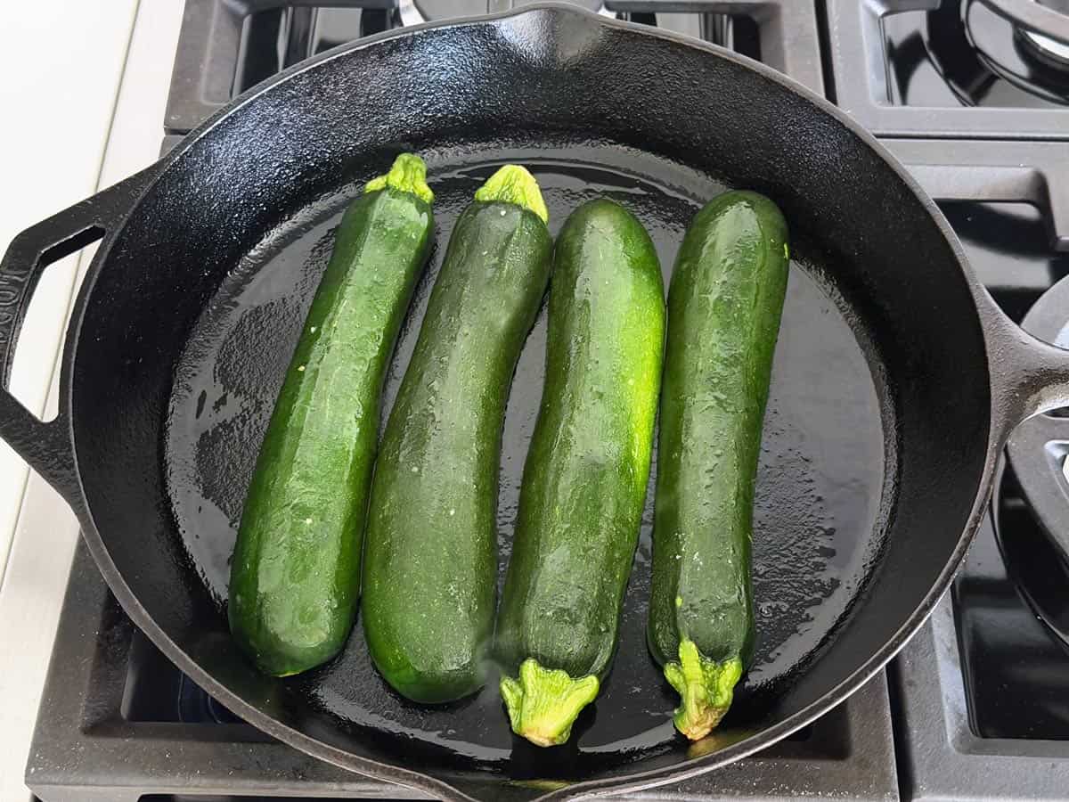 4 zucchini halves in a cast-iron skillet.