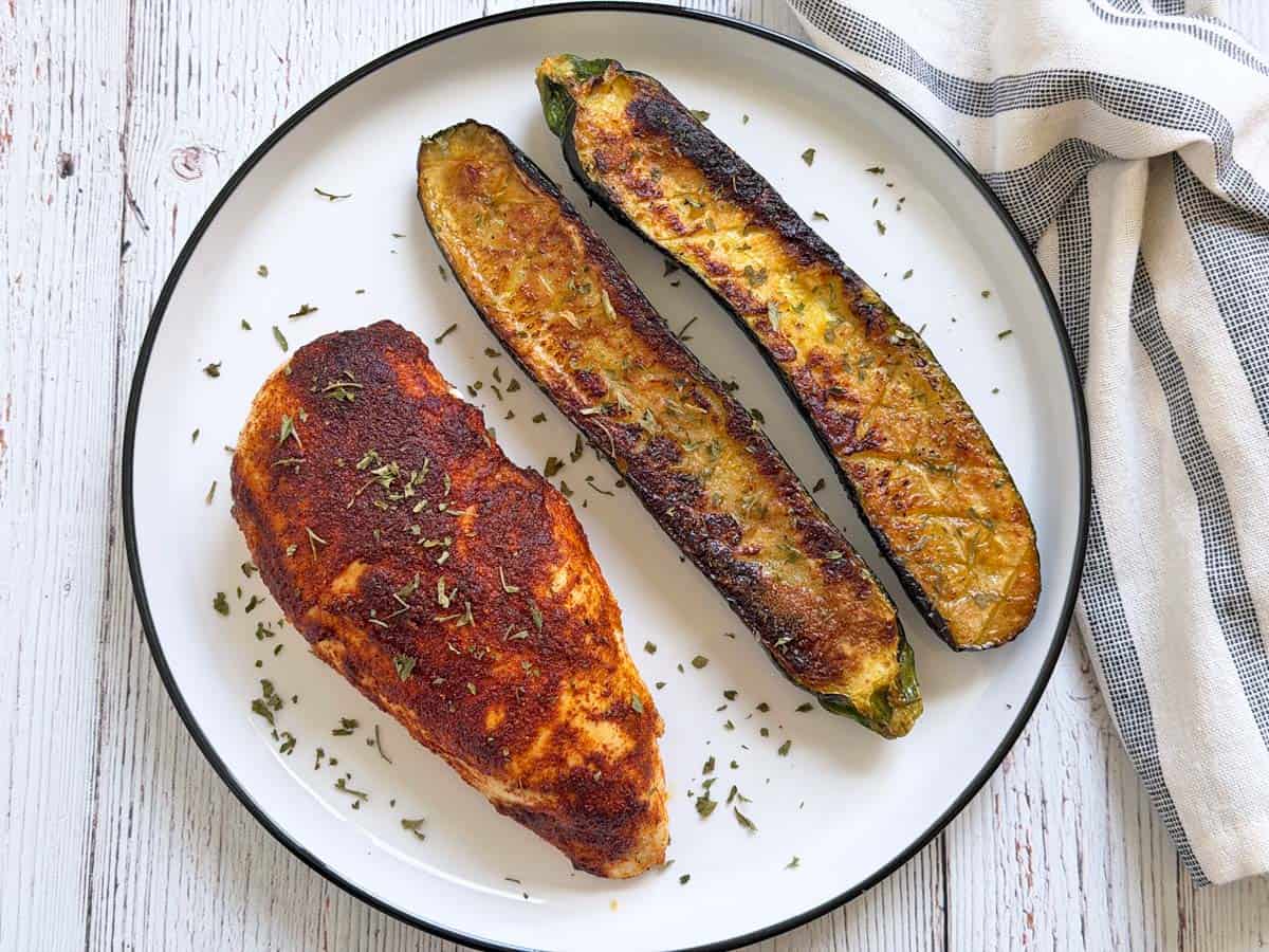 Roasted zucchini is served with blackened chicken.