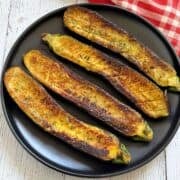 Roasted zucchini is served on a dark plate.