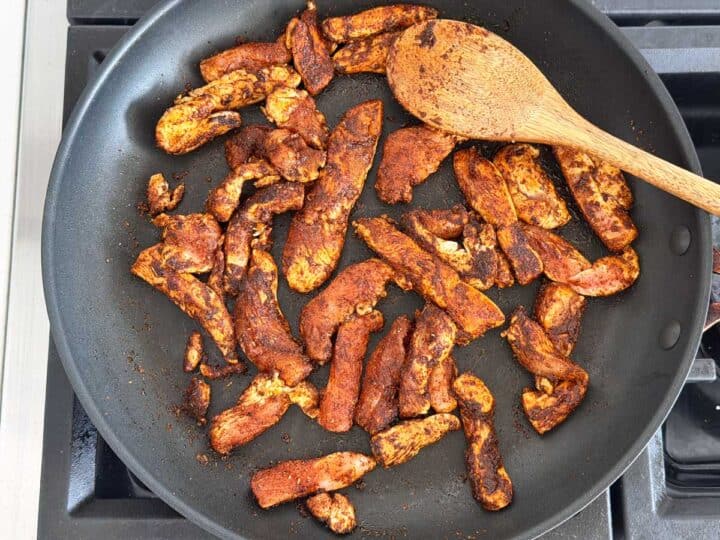 Sauteing chicken and seasonings in a skillet.