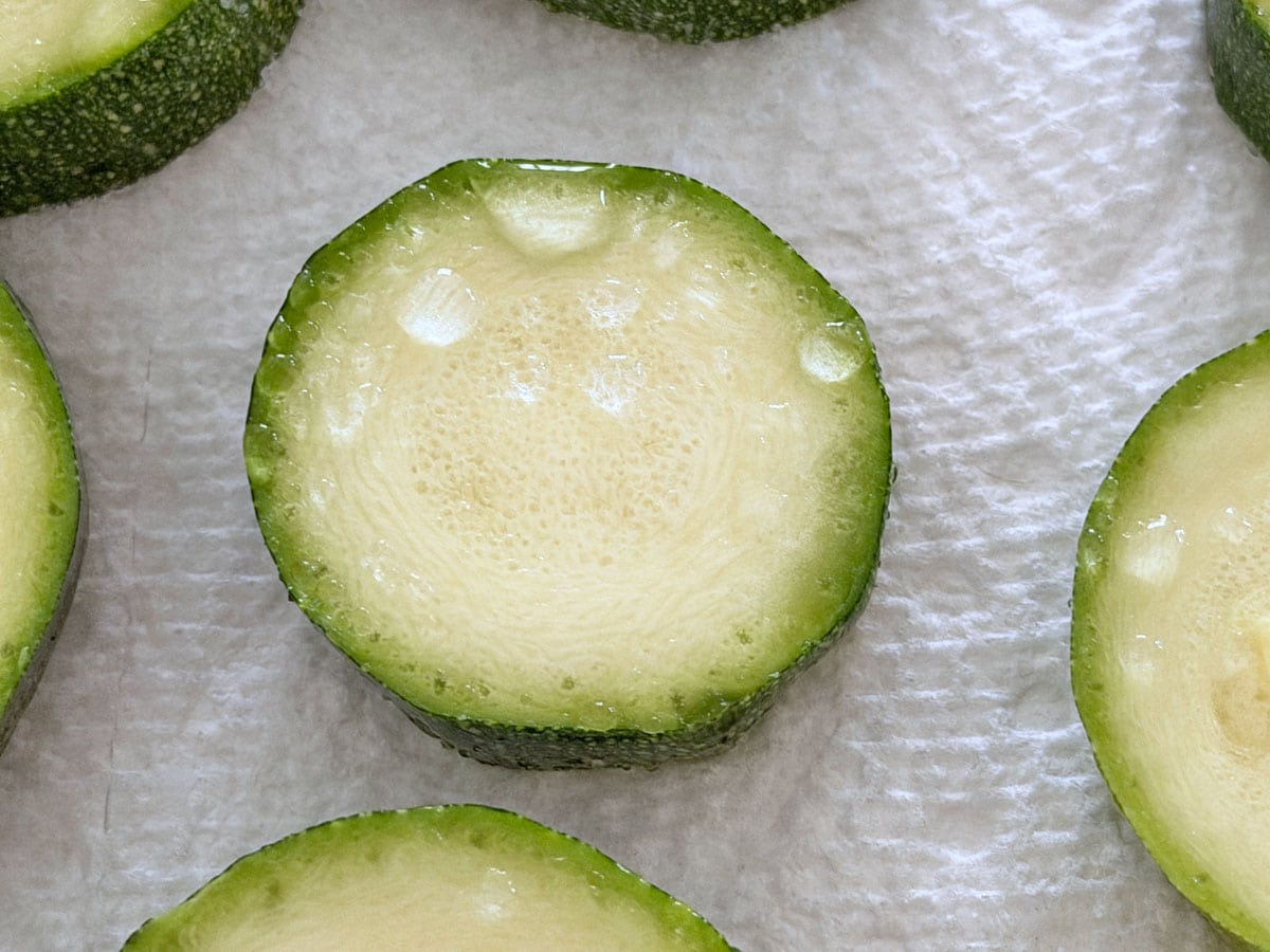 Water droplets on top of a salted zucchini slice.