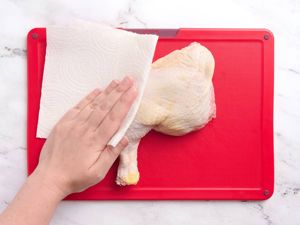 Patting the chicken dry with paper towels.