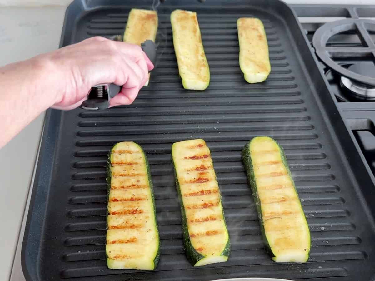 Flipping the zucchini slices on the grill.