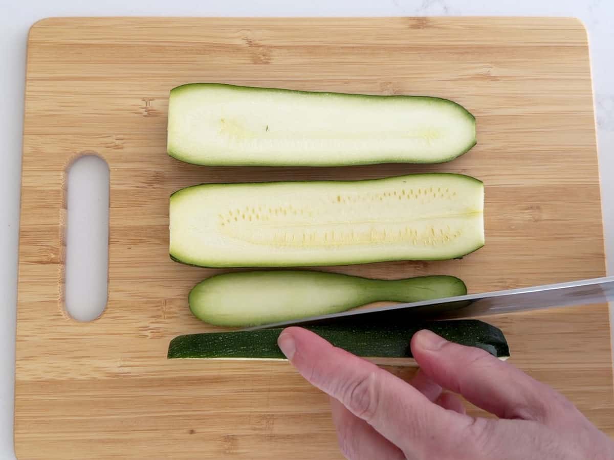Cutting a sliver off the zucchini's side.