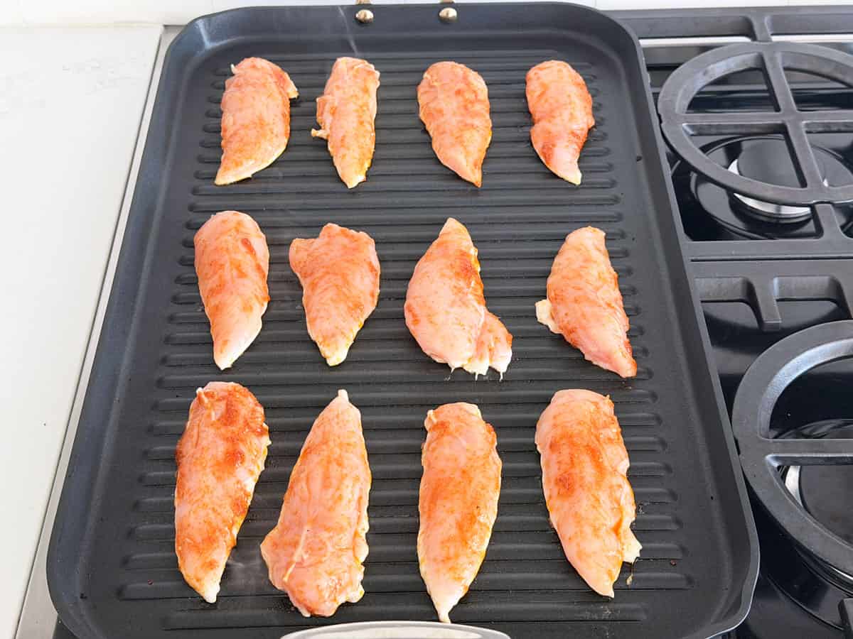 12 chicken tenders on a grill pan.