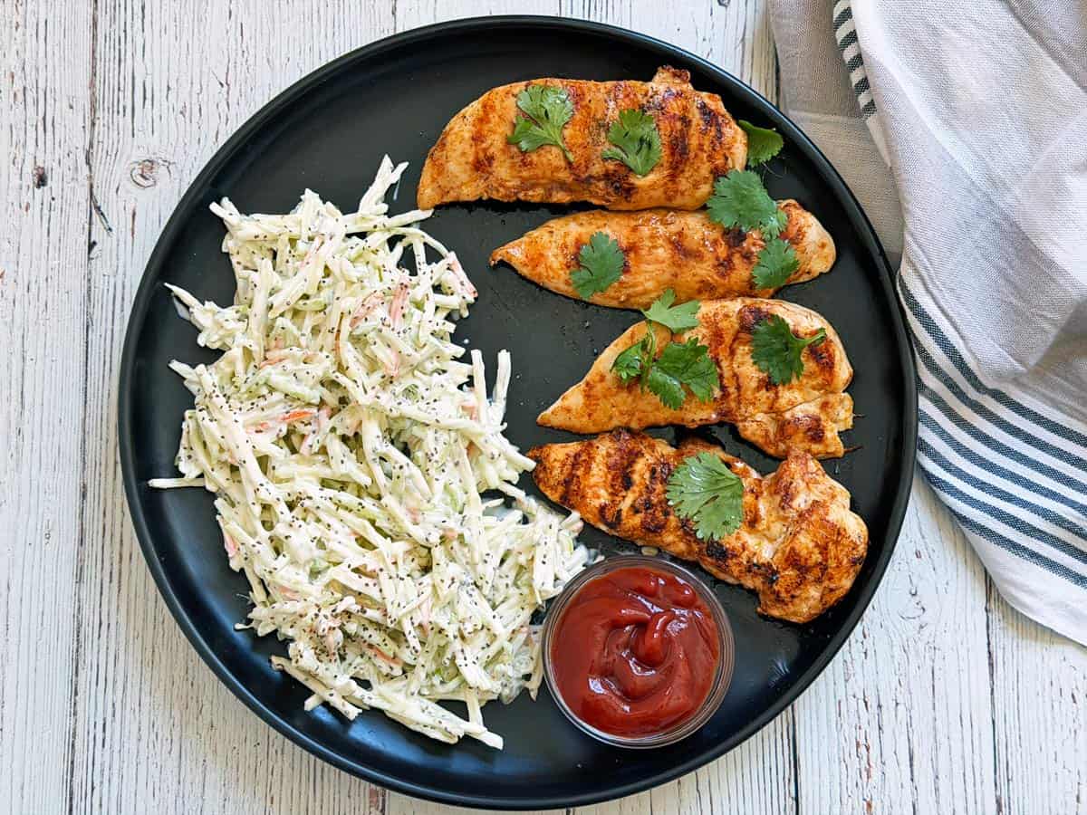 Grilled chicken tenders are served with coleslaw.