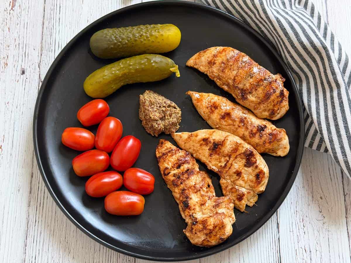 Leftover chicken tenders are served with tomatoes, pickles, and mustard.