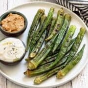 Grilled okra is served on a plate with dipping sauces.
