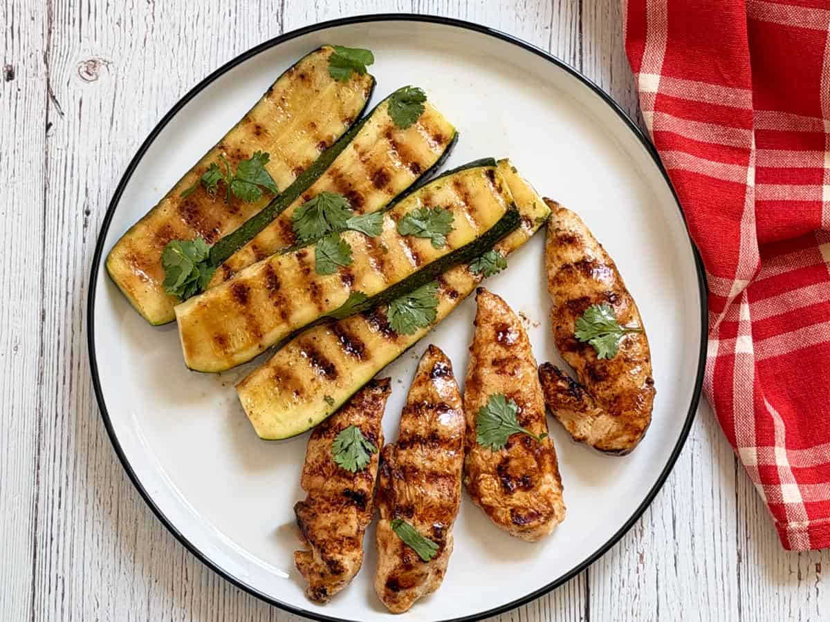Grilled zucchini is served with chicken tenders.