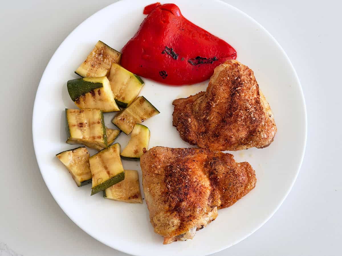 Leftover grilled zucchini are served with chicken thighs.