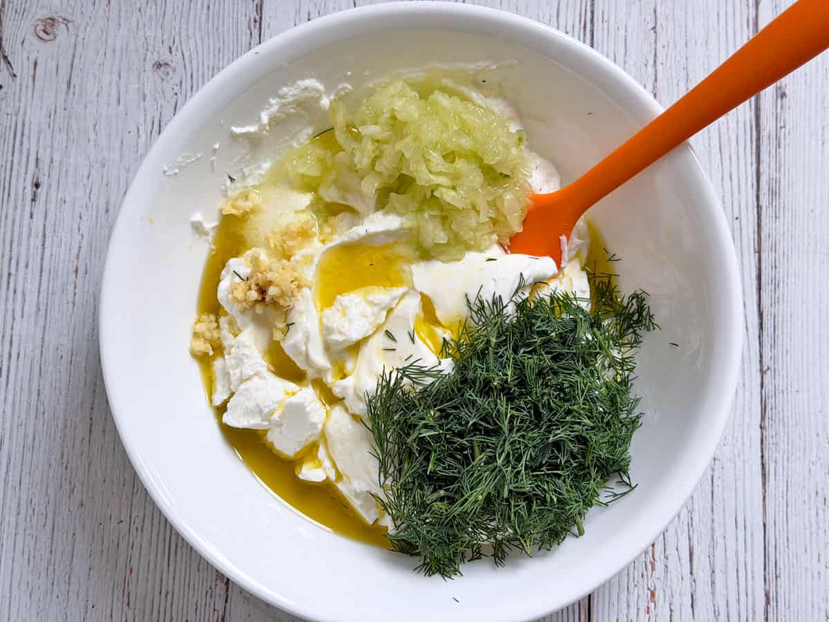 Tzatziki ingredients in the bowl include extra olive oil when using a lower-fat yogurt.