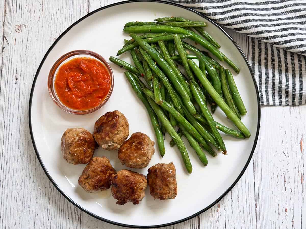 Turkey meatballs are served with a dipping sauce and green beans.