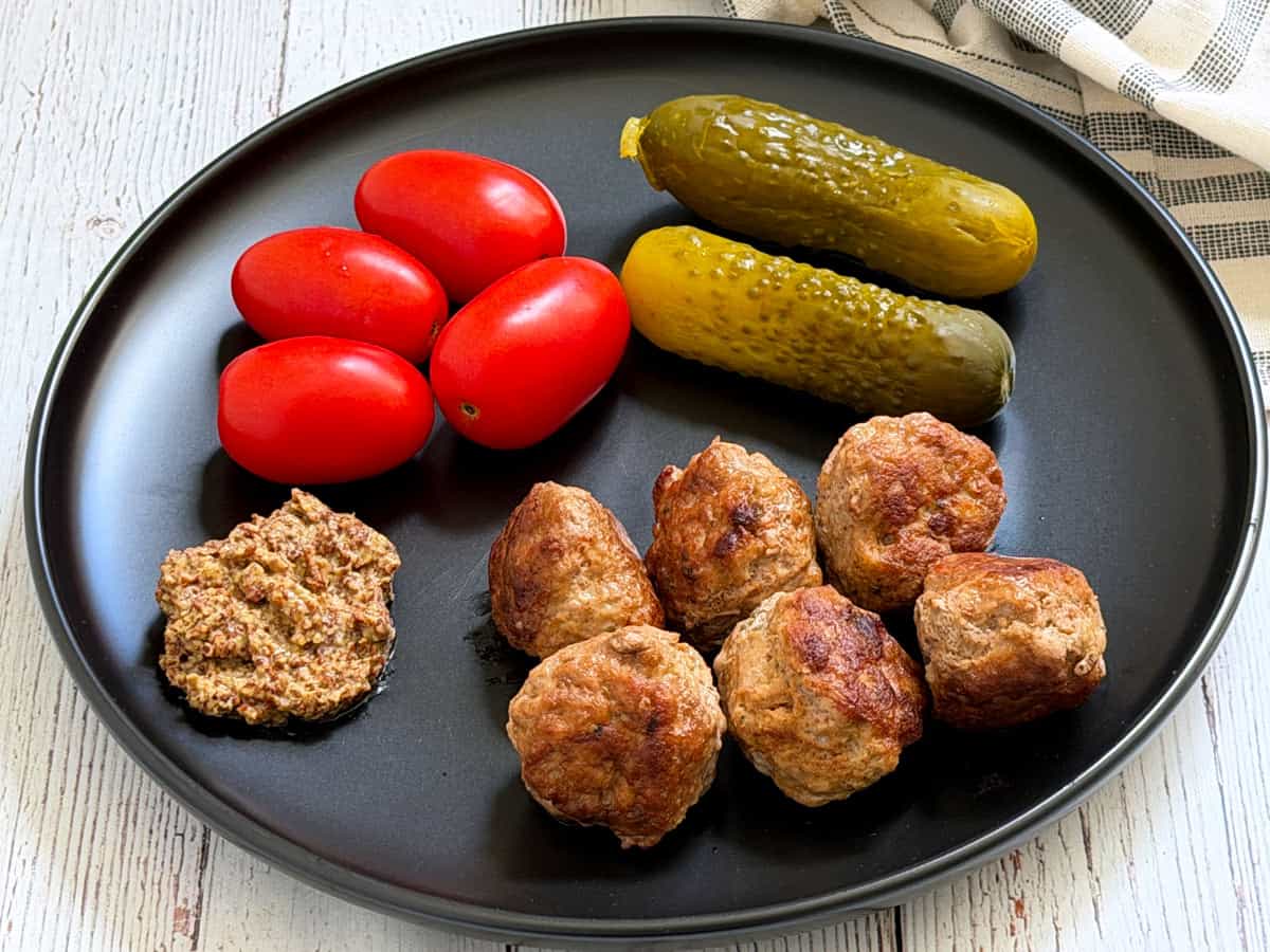 Turkey meatballs leftovers are served with tomatoes, pickles, and mustard.